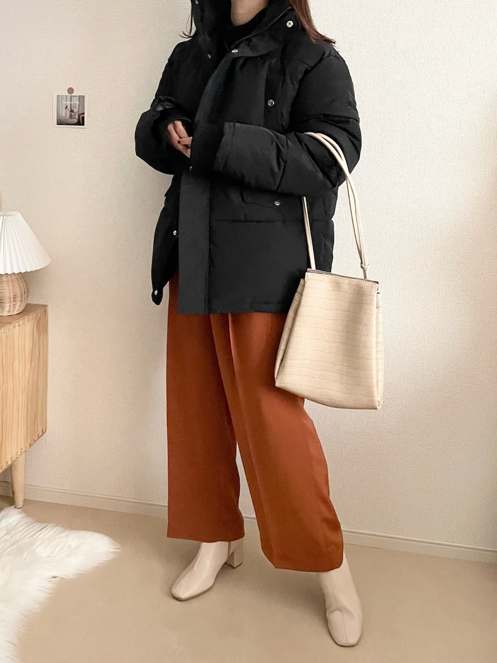 ブラック系のダウンジャケット/コート、ブラック系のスカート、ホワイト系のハンドバッグを着用したレディースの冬コーディネートの3枚目の写真