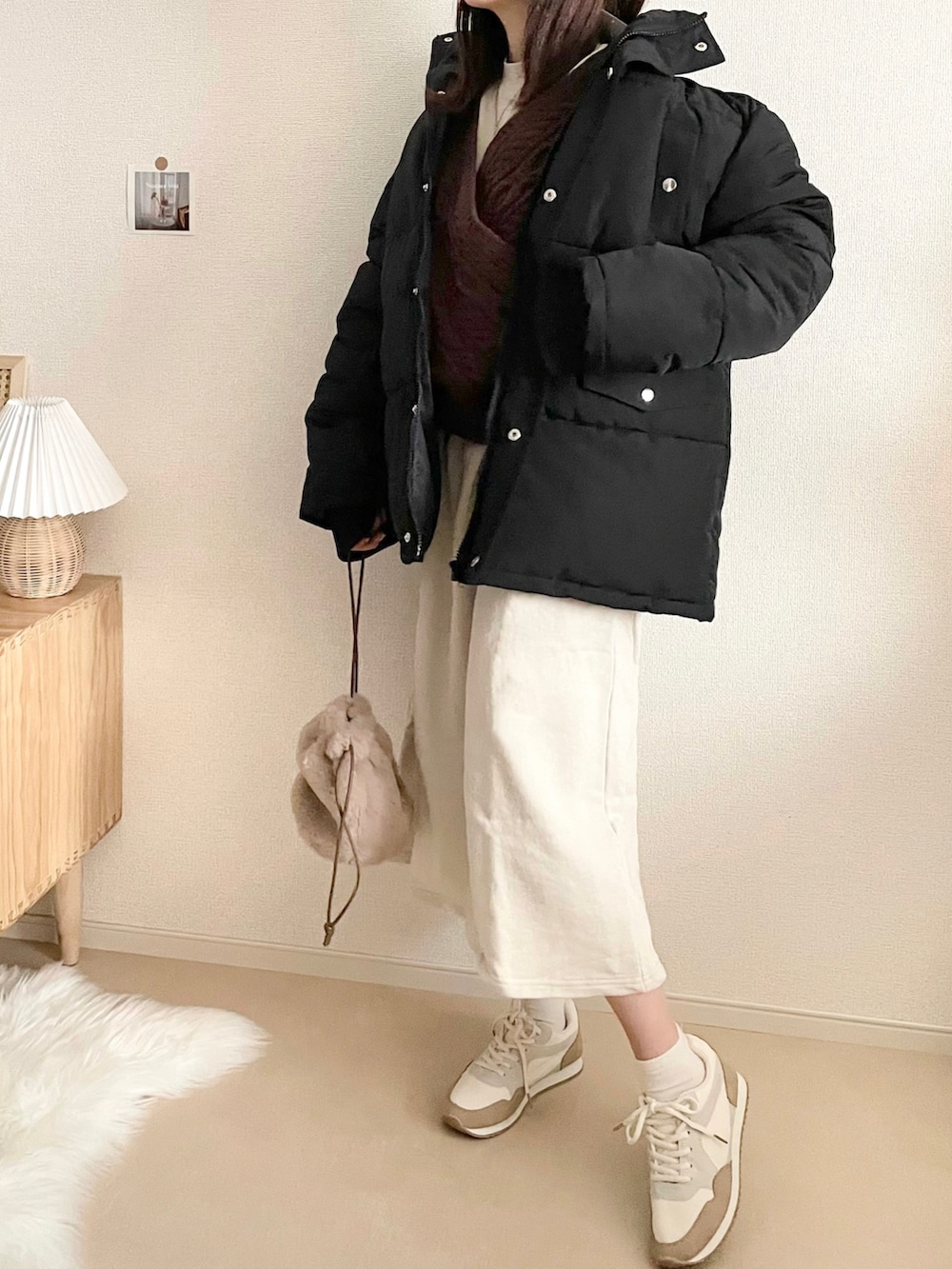 ブラック系のダウンジャケット/コート、ブラック系のスカート、ホワイト系のハンドバッグを着用したレディースの冬コーディネートの4枚目の写真