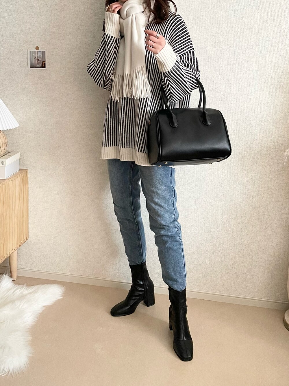 ブラック系のニット/セーター、ブルー系のデニムパンツ、ブラック系のボストンバッグを着用したレディースの冬コーディネートの2枚目の写真