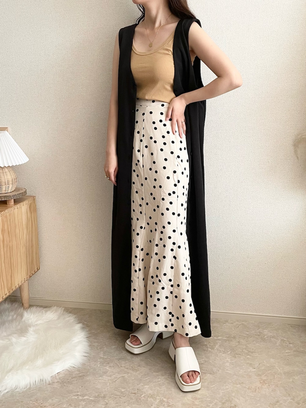 イエロー系のタンクトップ、ベージュ系のスカート、ブラック系のジャンパースカートを着用したレディースの夏コーディネートの2枚目の写真