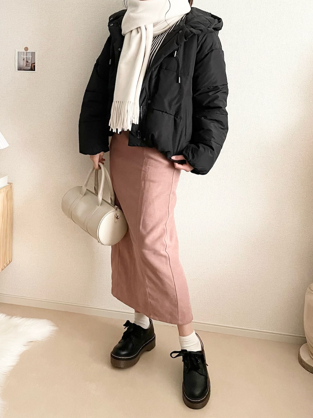 ピンク系のスカート、ブラック系のニット/セーター、ホワイト系のショルダーバッグを着用したレディースの冬コーディネートの2枚目の写真