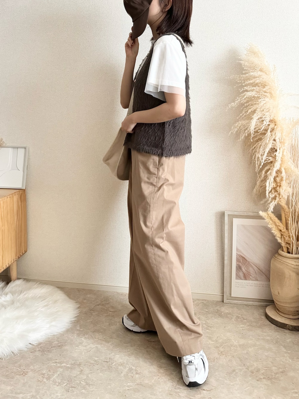 グレー系のベスト、ベージュ系のチノパンツ、ブラック系のショルダーバッグを着用したレディースの秋コーディネートの2枚目の写真