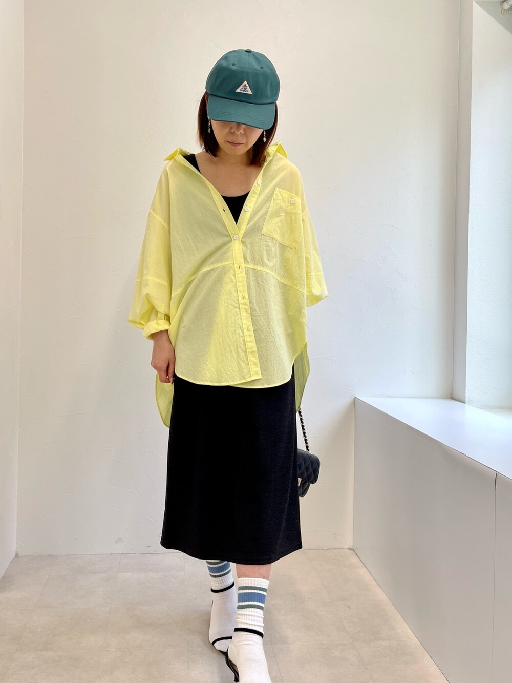 ブラック系のタンクトップ、ブラック系のスカート、イエロー系のシャツ/ブラウスを着用したレディースの春コーディネートの5枚目の写真