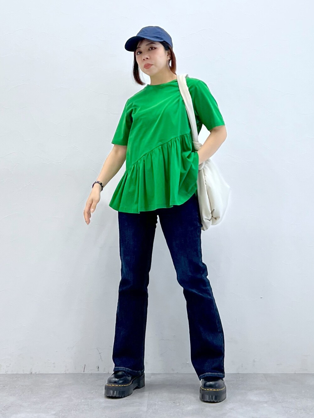 グリーン系のトップス、ブルー系のパンツ、ブラック系のブーツを着用したレディースの春コーディネートの3枚目の写真