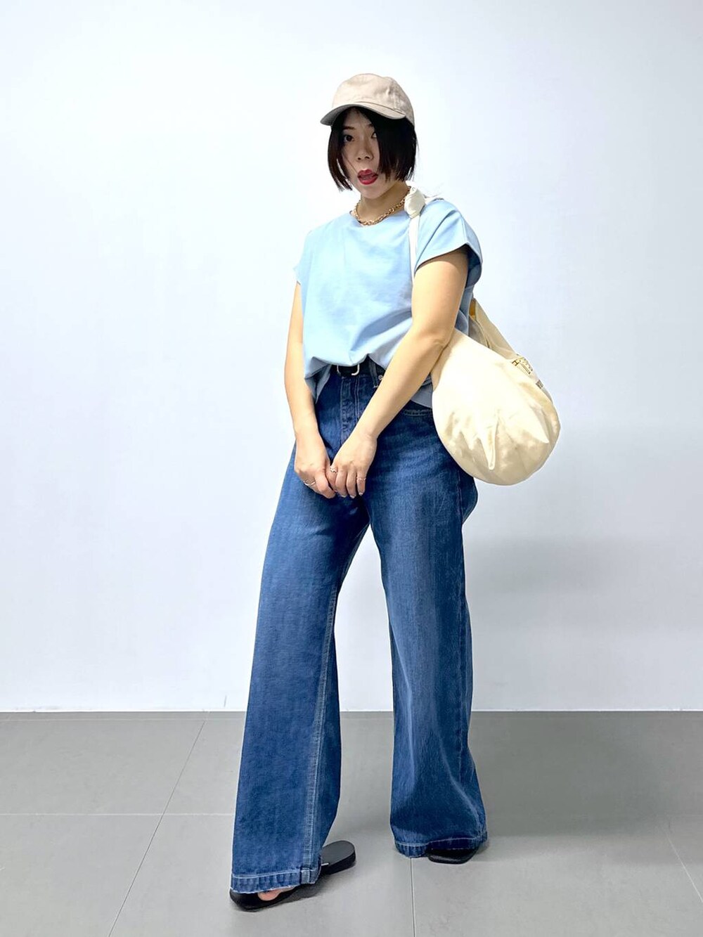 ベージュ系のトートバッグ、ブルー系のデニムパンツ、その他のサンダルを着用したレディースの夏コーディネートの2枚目の写真