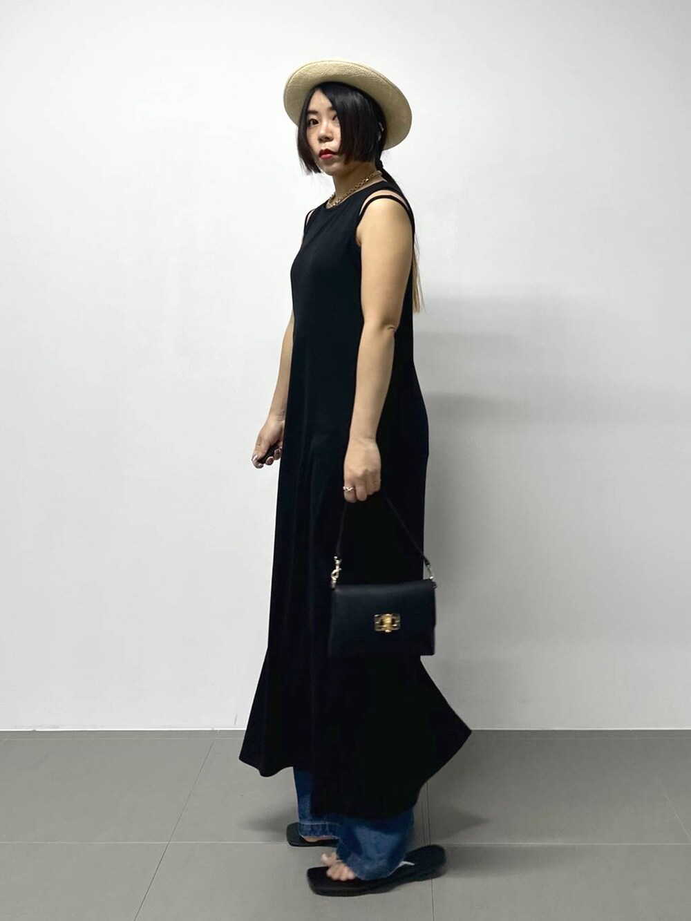 ブラック系のショルダーバッグ、ブルー系のデニムパンツ、その他のサンダルを着用したレディースの夏コーディネートの3枚目の写真
