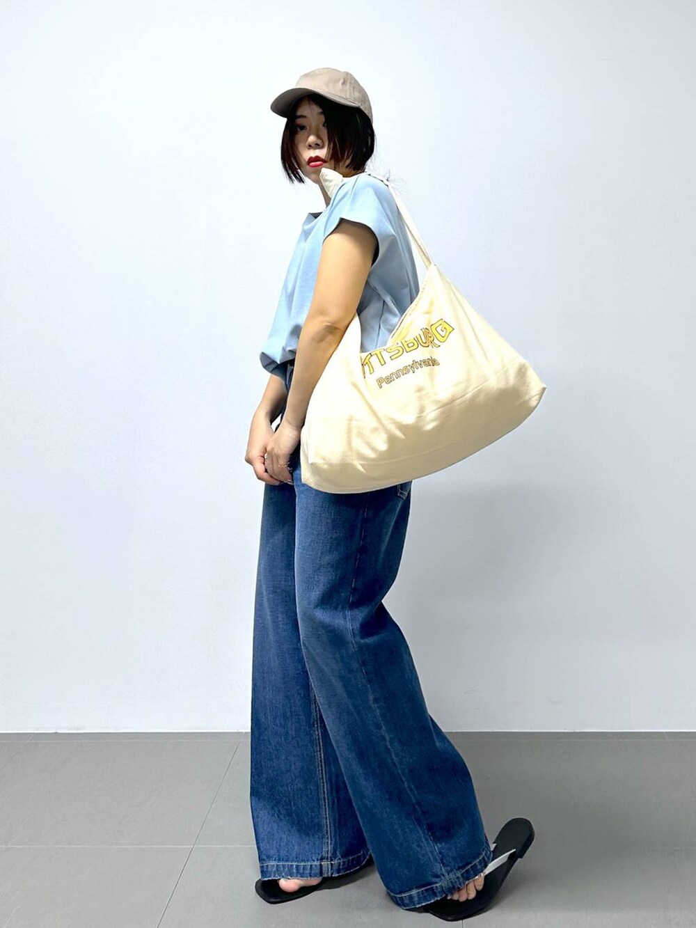 ベージュ系のトートバッグ、ブルー系のデニムパンツ、その他のサンダルを着用したレディースの夏コーディネートの3枚目の写真