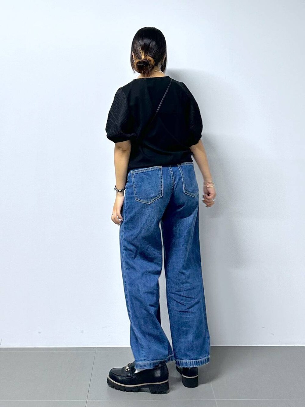 ブラック系のショルダーバッグ、ブルー系のデニムパンツ、ブラック系のローファーを着用したレディースの夏コーディネートの5枚目の写真