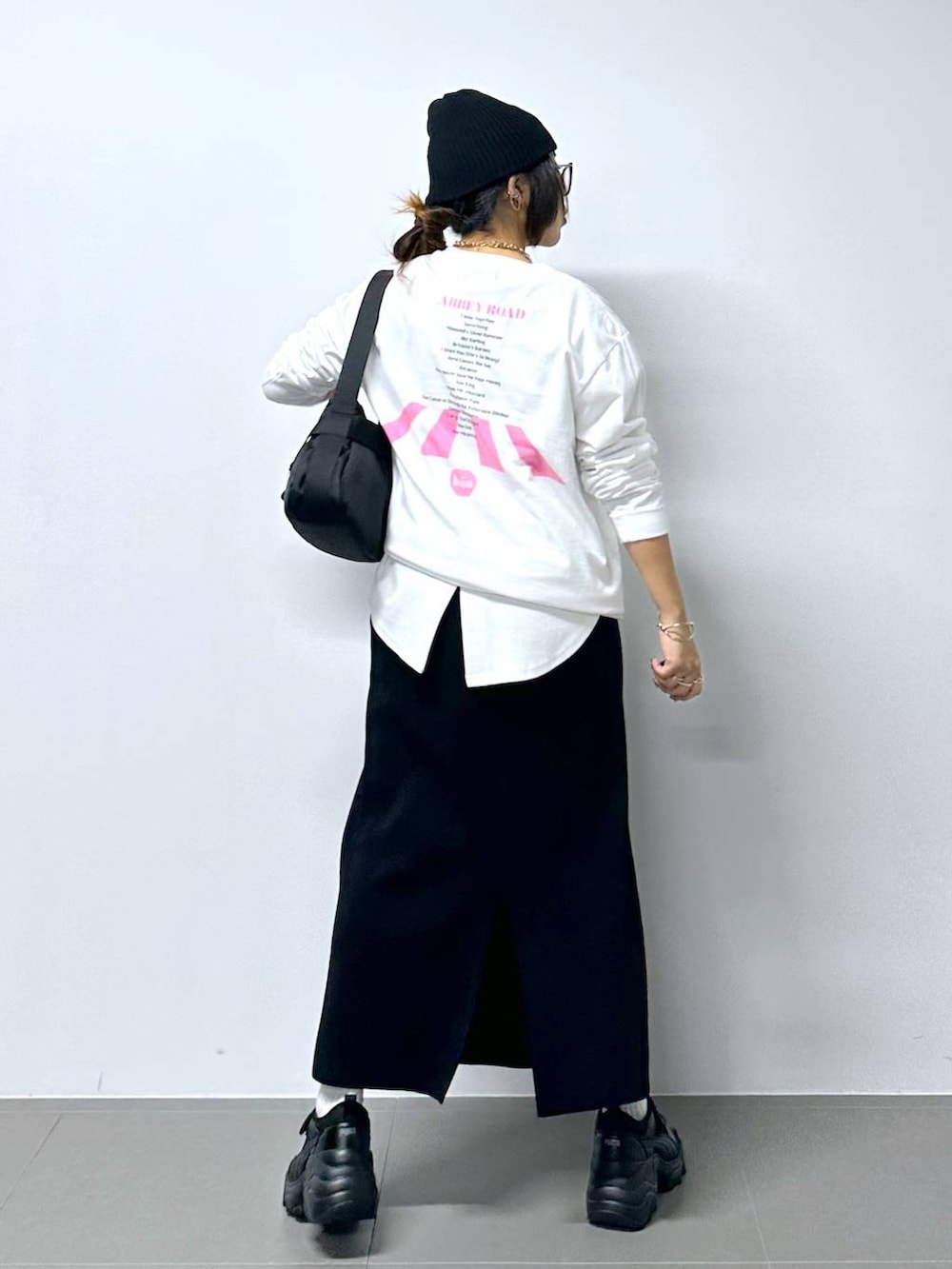 ブラック系のスニーカー、ホワイト系のTシャツ/カットソー、ブラック系のショルダーバッグを着用したレディースの夏コーディネートの3枚目の写真