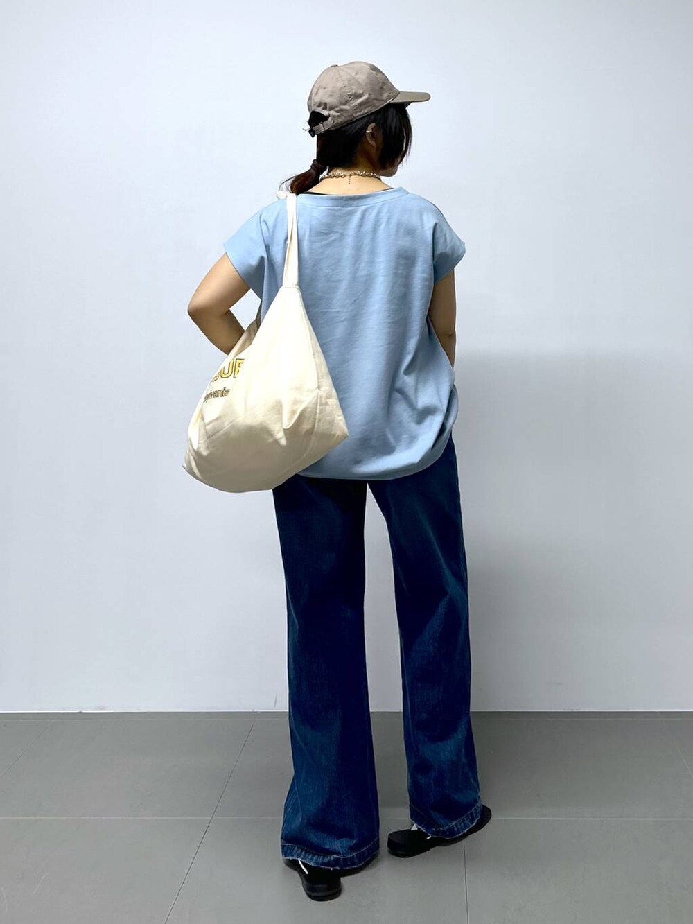 ベージュ系のトートバッグ、ブルー系のデニムパンツ、その他のサンダルを着用したレディースの夏コーディネートの4枚目の写真