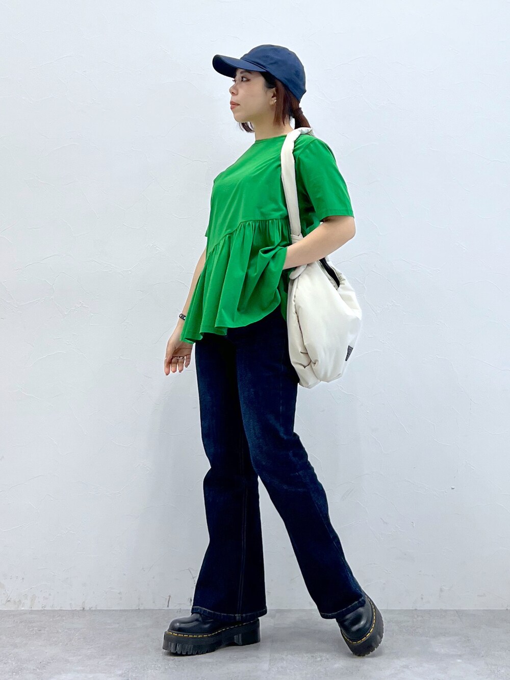 グリーン系のトップス、ブルー系のパンツ、ブラック系のブーツを着用したレディースの春コーディネートの2枚目の写真