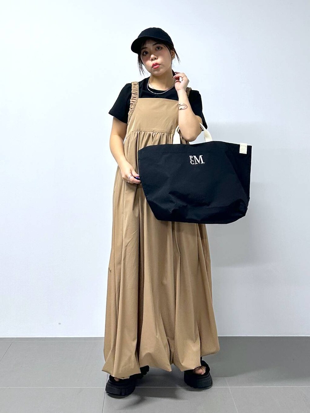 ベージュ系のワンピース、ブラック系のTシャツ/カットソーを着用したレディースの春コーディネートの2枚目の写真