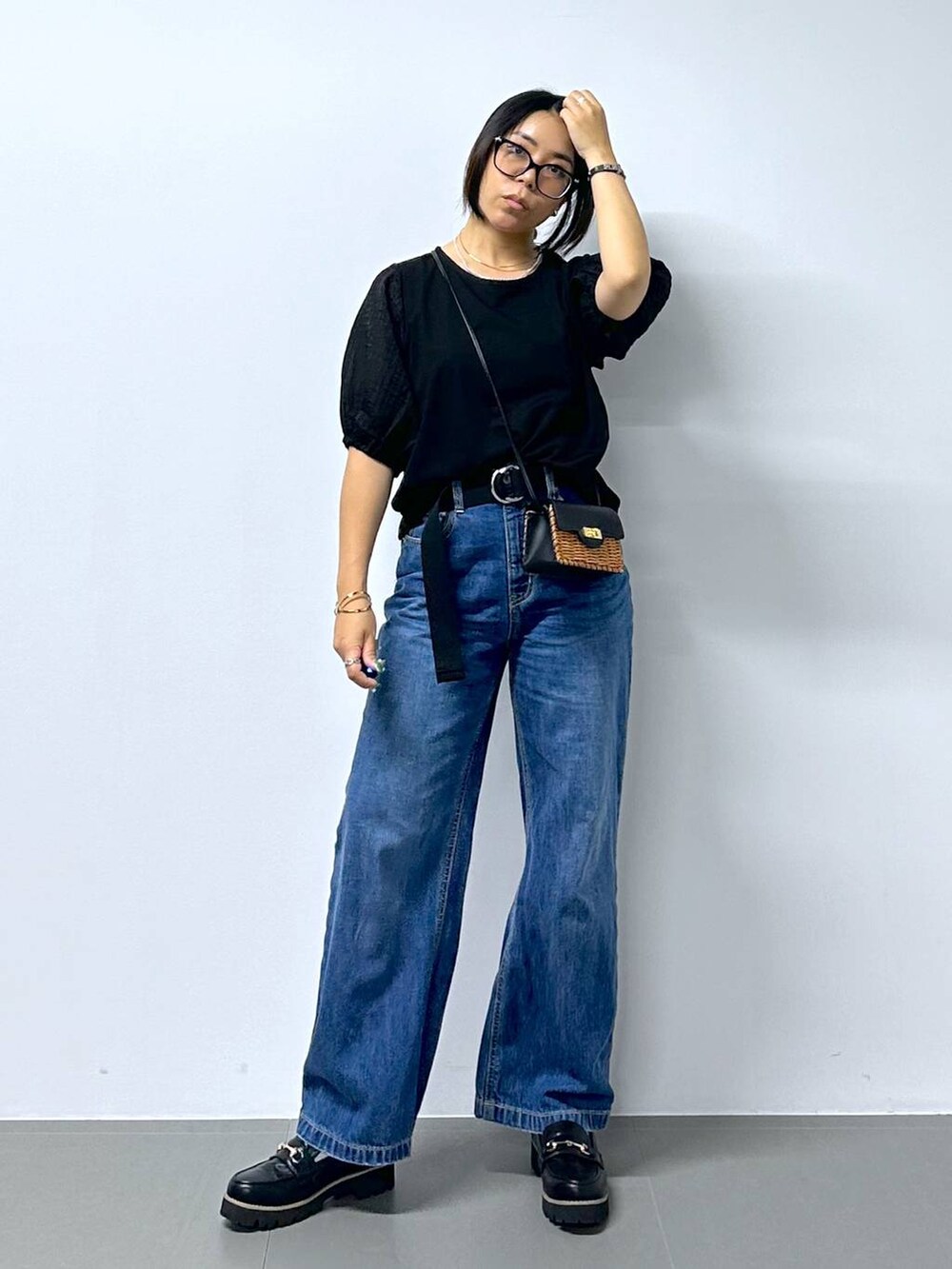 ブラック系のショルダーバッグ、ブルー系のデニムパンツ、ブラック系のローファーを着用したレディースの夏コーディネートの2枚目の写真