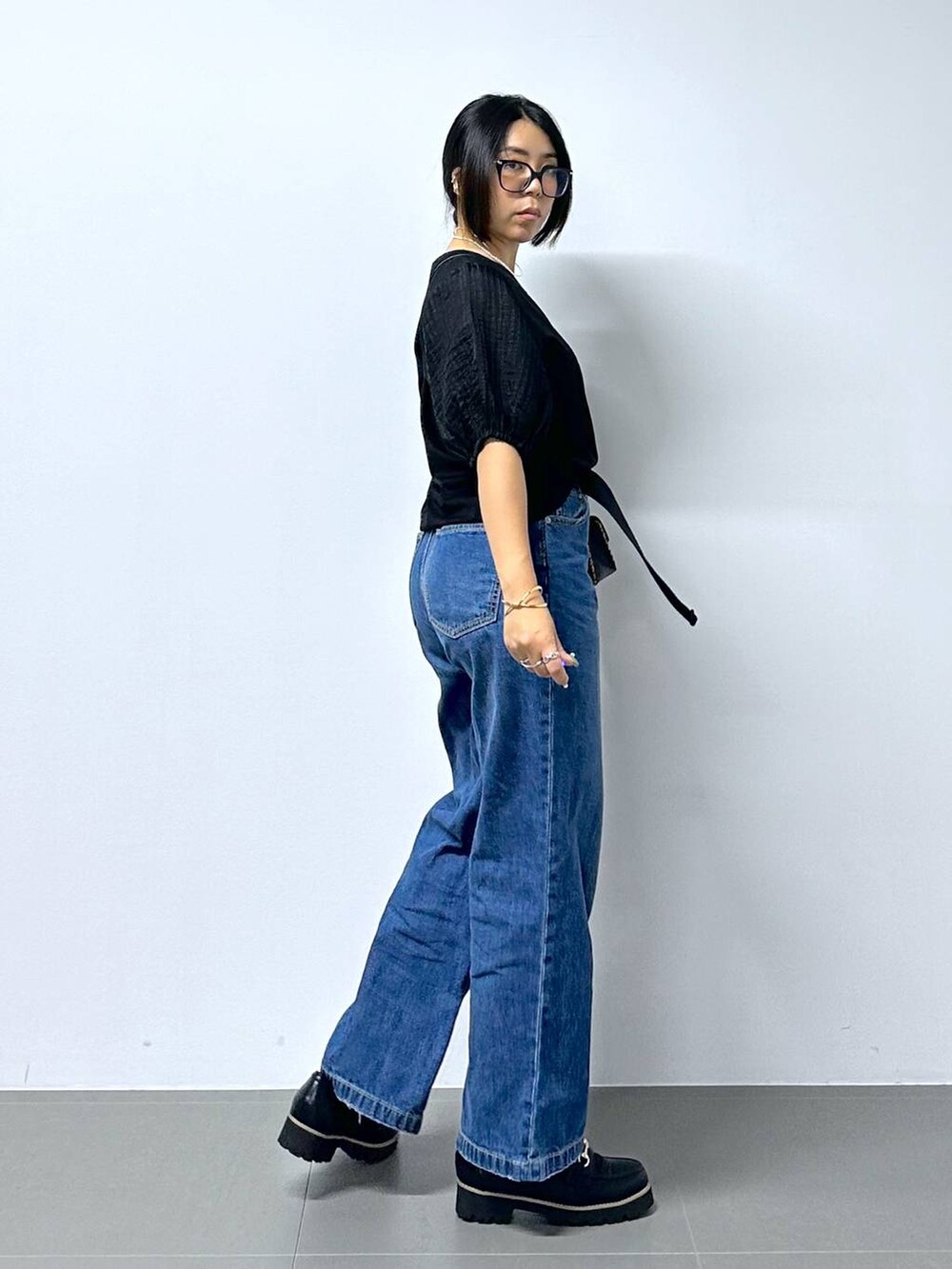 ブラック系のショルダーバッグ、ブルー系のデニムパンツ、ブラック系のローファーを着用したレディースの夏コーディネートの3枚目の写真