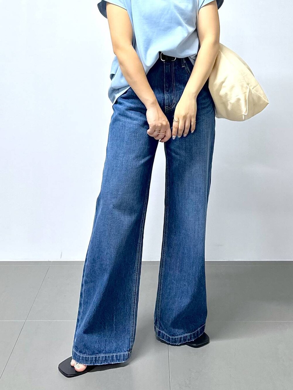 ベージュ系のトートバッグ、ブルー系のデニムパンツ、その他のサンダルを着用したレディースの夏コーディネートの5枚目の写真