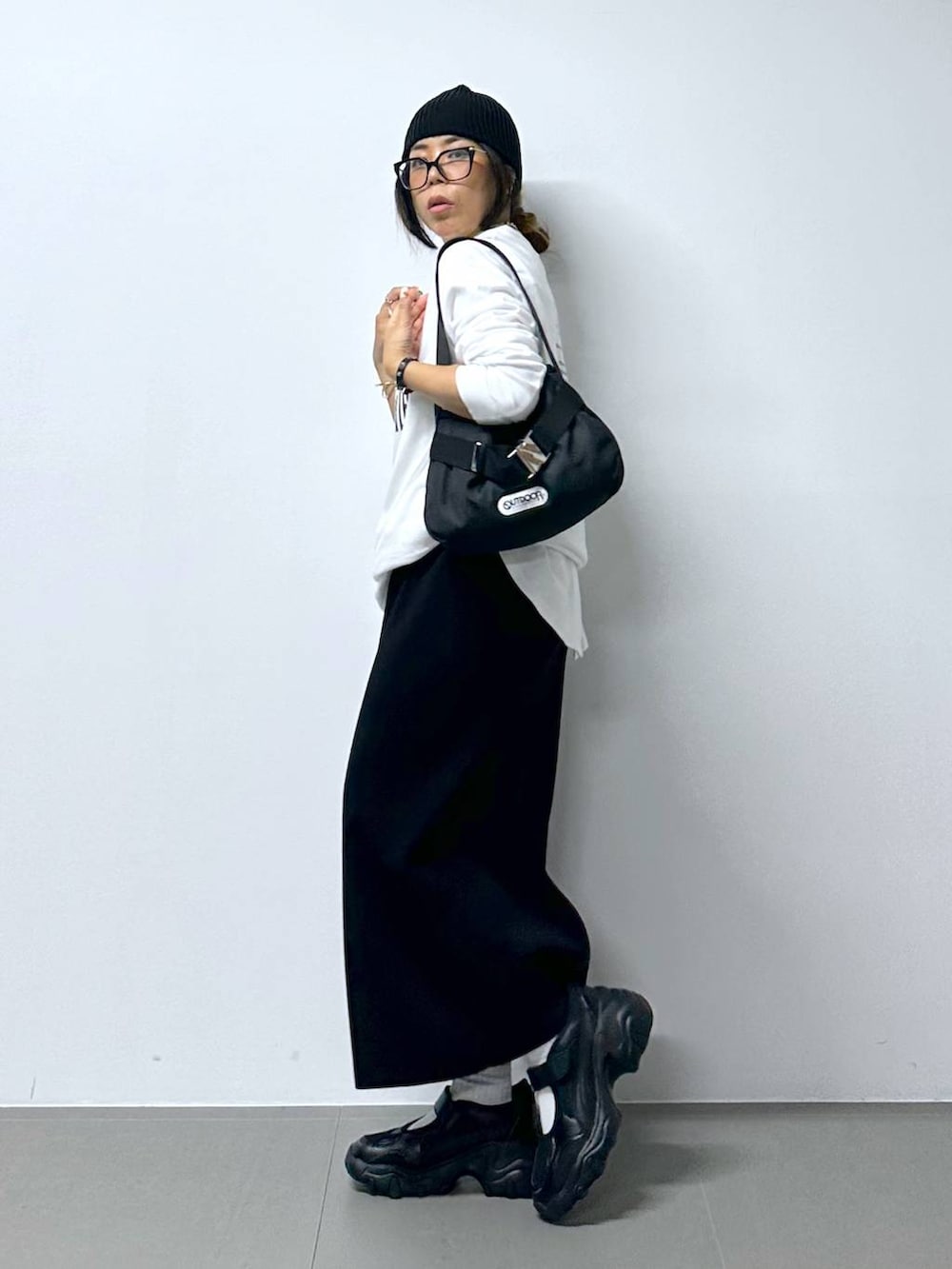 ブラック系のスニーカー、ホワイト系のTシャツ/カットソー、ブラック系のショルダーバッグを着用したレディースの夏コーディネートの4枚目の写真