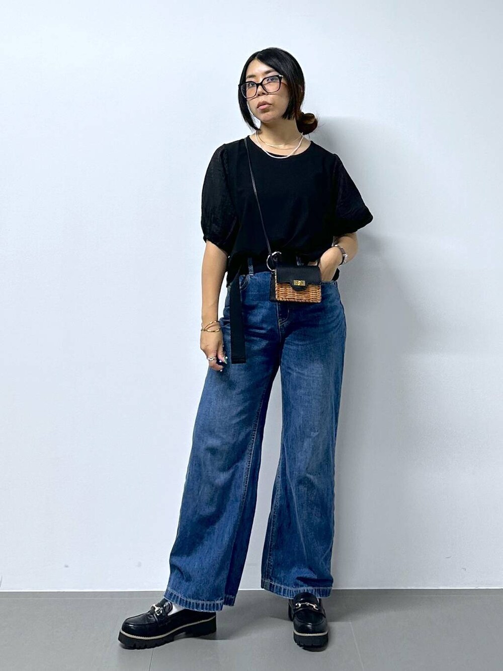 ブラック系のショルダーバッグ、ブルー系のデニムパンツ、ブラック系のローファーを着用したレディースの夏コーディネートの4枚目の写真