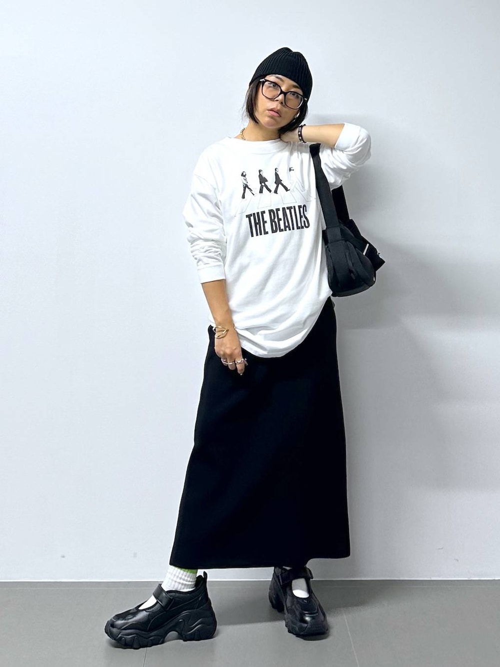 ブラック系のスニーカー、ホワイト系のTシャツ/カットソー、ブラック系のショルダーバッグを着用したレディースの夏コーディネートの2枚目の写真