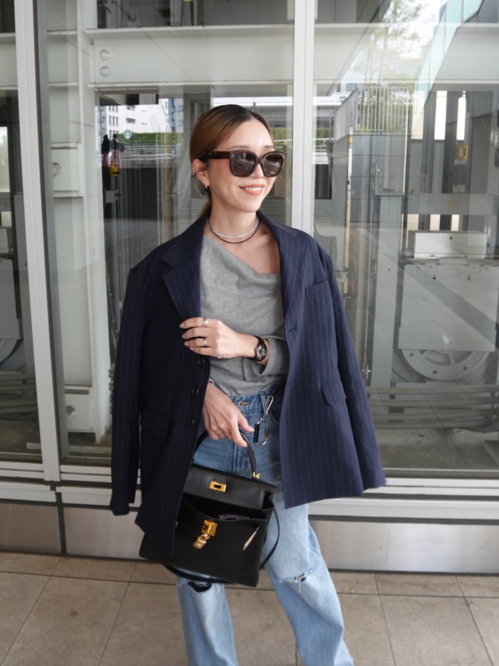 ブルー系のテーラードジャケット、ブルー系のデニムパンツ、ブラック系のバッグを着用したレディースの春コーディネートの3枚目の写真