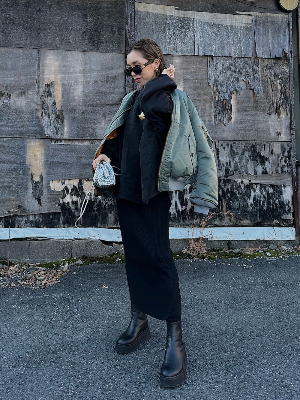 グリーン系のMA-1、シルバー系のバッグ、ブラック系のブーツを着用したレディースの冬コーディネートの2枚目の写真