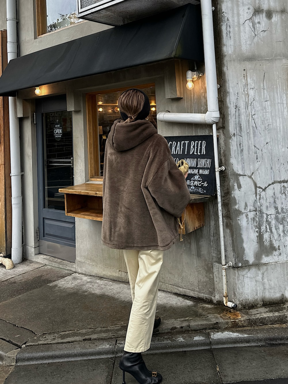 ブラウン系のブルゾン、ホワイト系のニット/セーター、ベージュ系のバッグを着用したレディースの冬コーディネートの5枚目の写真