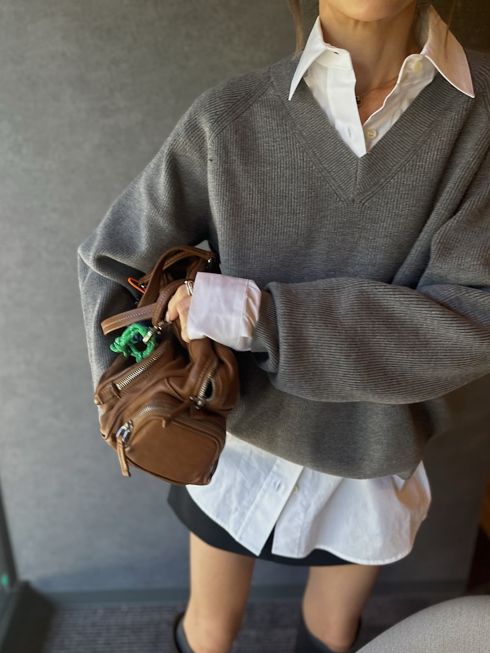 グレー系のニット/セーター、ブラック系のブーツ、ブラウン系のバッグを着用したレディースの冬コーディネートの2枚目の写真