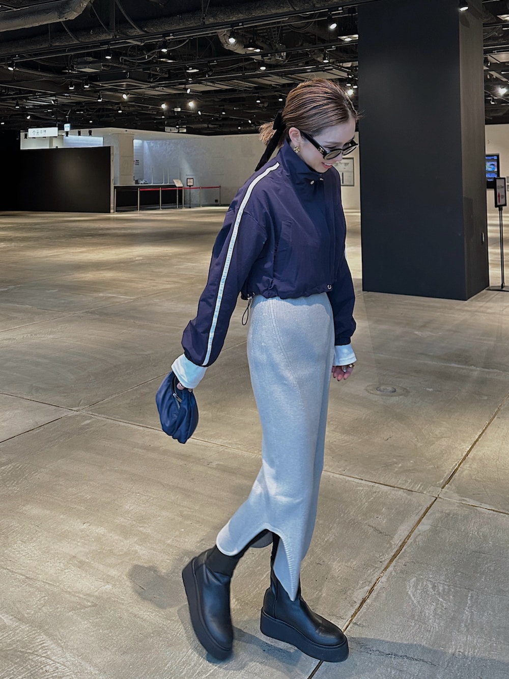 ブルー系のブルゾン、ブルー系のバッグ、ブラック系のブーツを着用したレディースの冬コーディネートの2枚目の写真