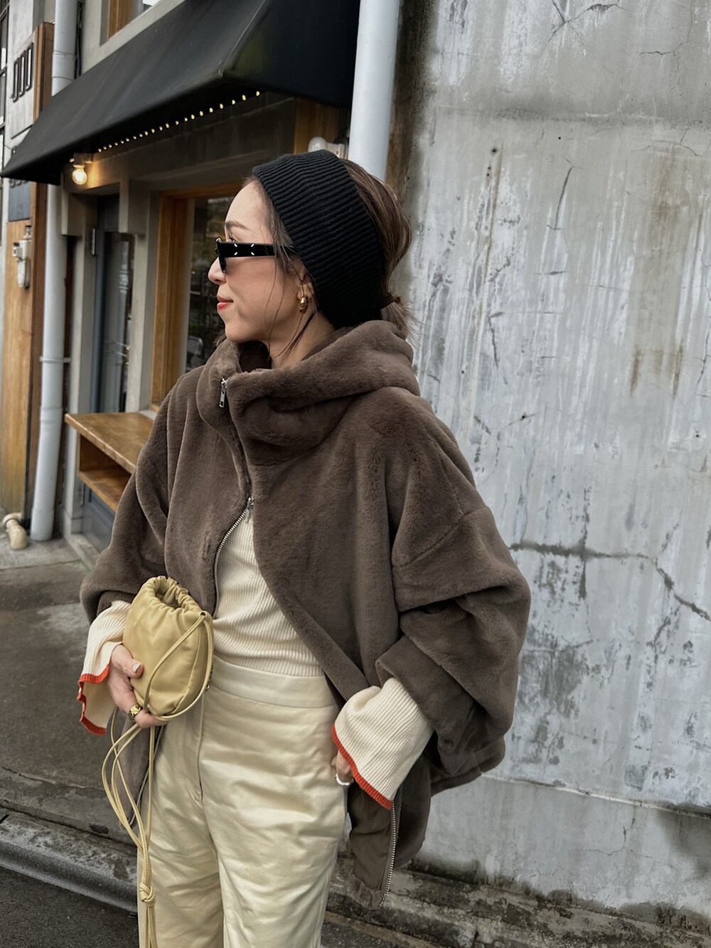 ブラウン系のブルゾン、ホワイト系のニット/セーター、ベージュ系のバッグを着用したレディースの冬コーディネートの4枚目の写真