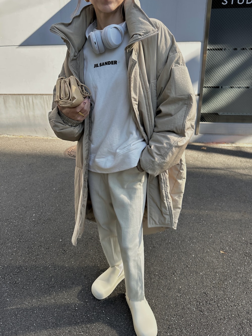 グリーン系のダウンジャケット/コート、ホワイト系のスウェット、ベージュ系のバッグを着用したレディースの冬コーディネートの2枚目の写真