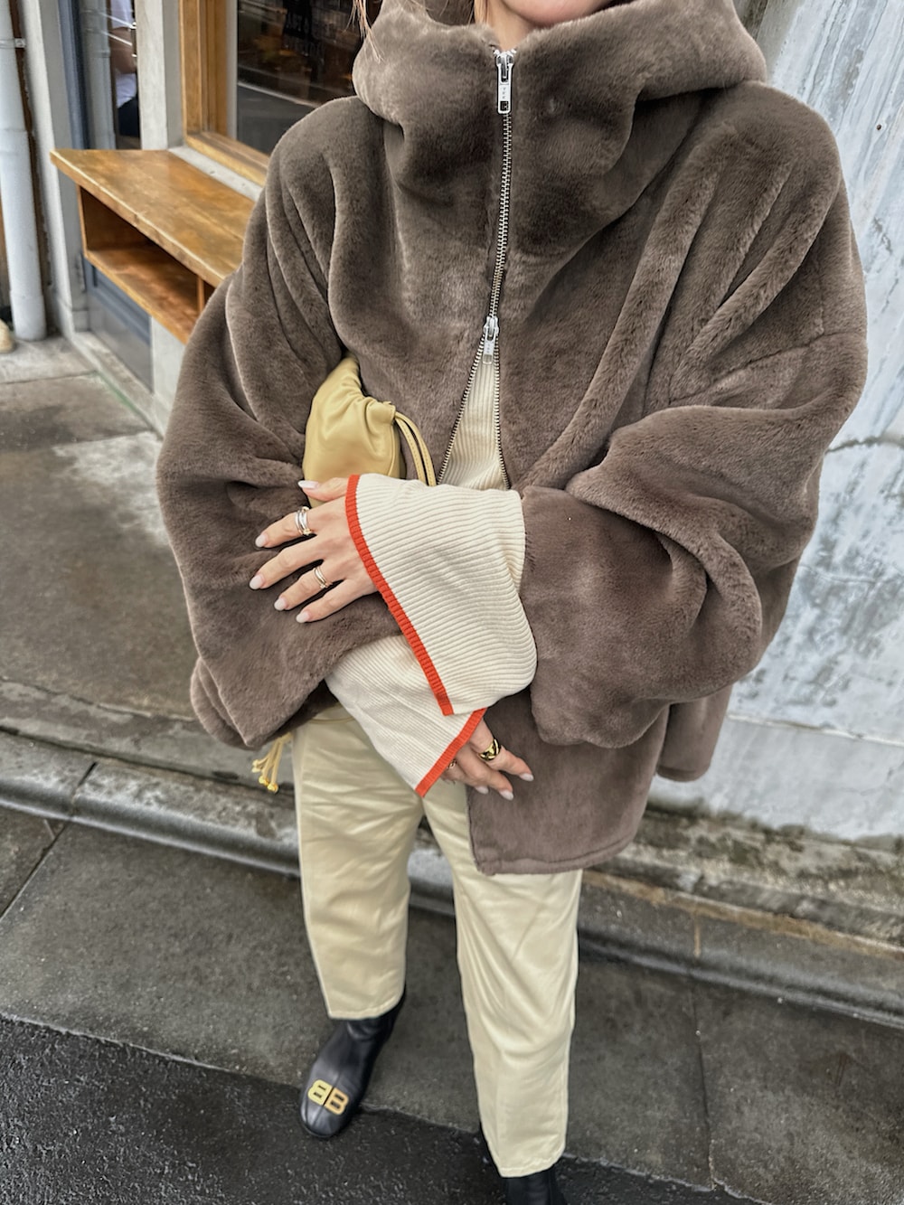 ブラウン系のブルゾン、ホワイト系のニット/セーター、ベージュ系のバッグを着用したレディースの冬コーディネートの2枚目の写真