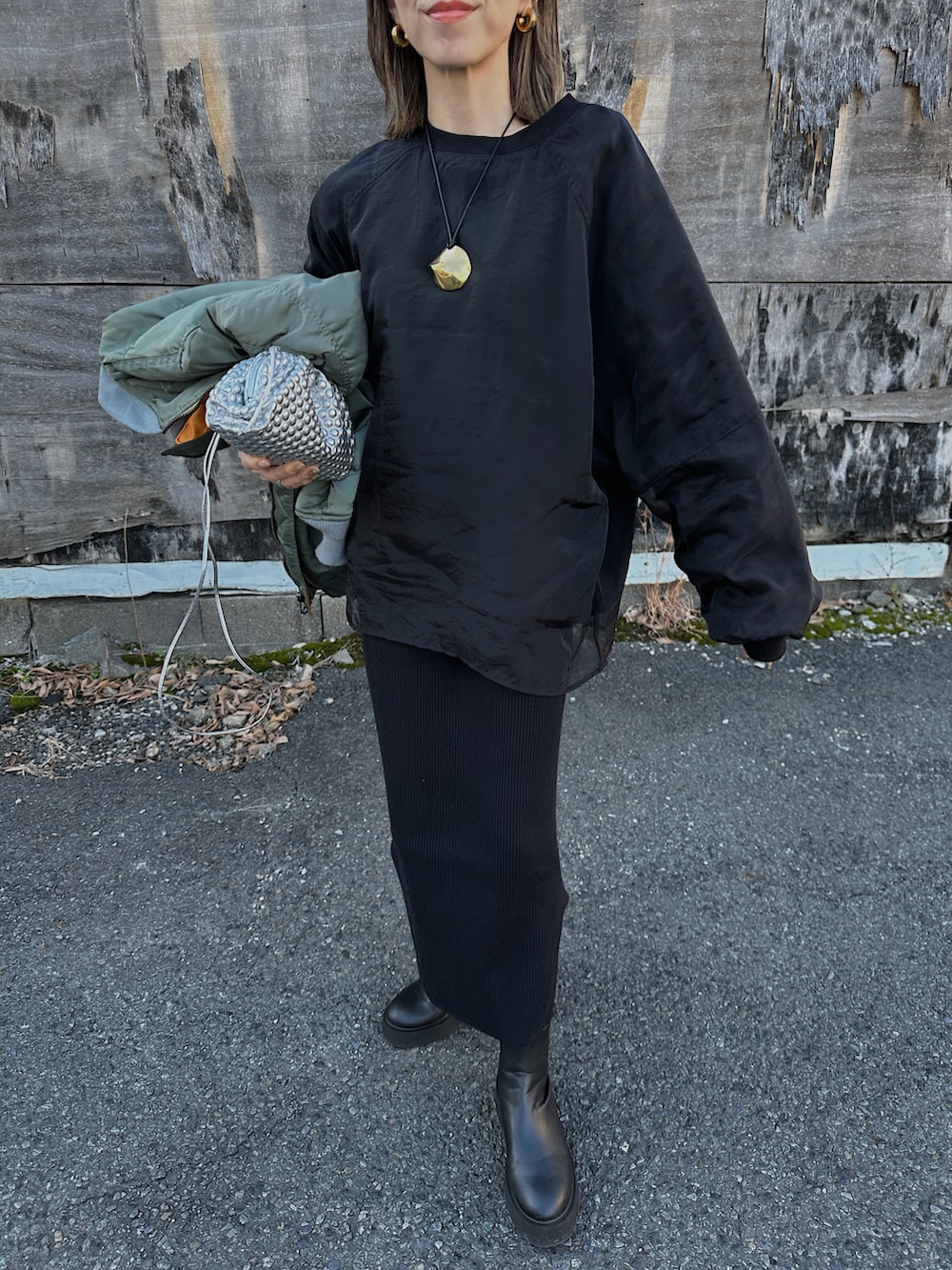 グリーン系のMA-1、シルバー系のバッグ、ブラック系のブーツを着用したレディースの冬コーディネートの4枚目の写真