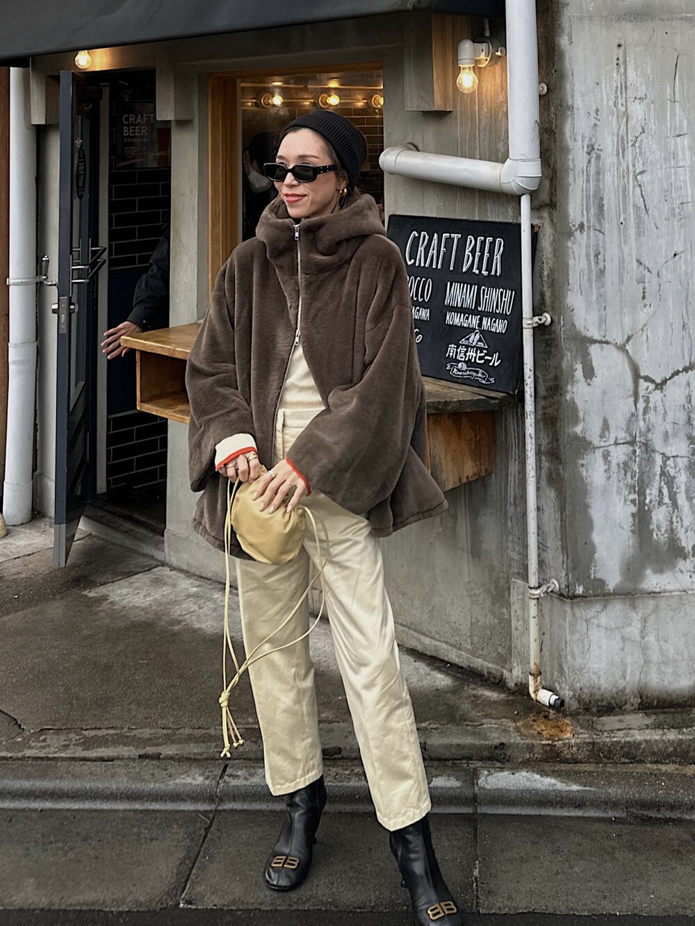 ブラウン系のブルゾン、ホワイト系のニット/セーター、ベージュ系のバッグを着用したレディースの冬コーディネートの3枚目の写真