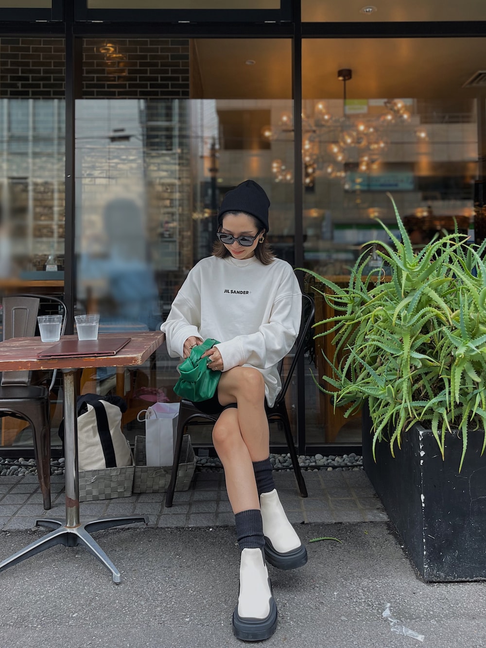 ホワイト系のスウェット、ホワイト系のブーツ、グリーン系のバッグを着用したレディースの秋コーディネートの2枚目の写真