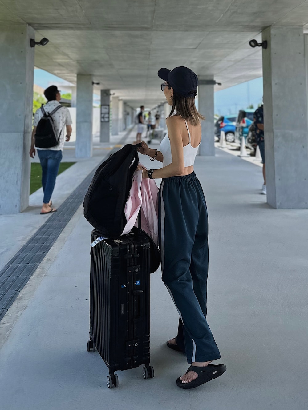 ブルー系のパンツ、ブラック系のサンダル、ブラック系のハンドバッグを着用したレディースの夏コーディネートの2枚目の写真