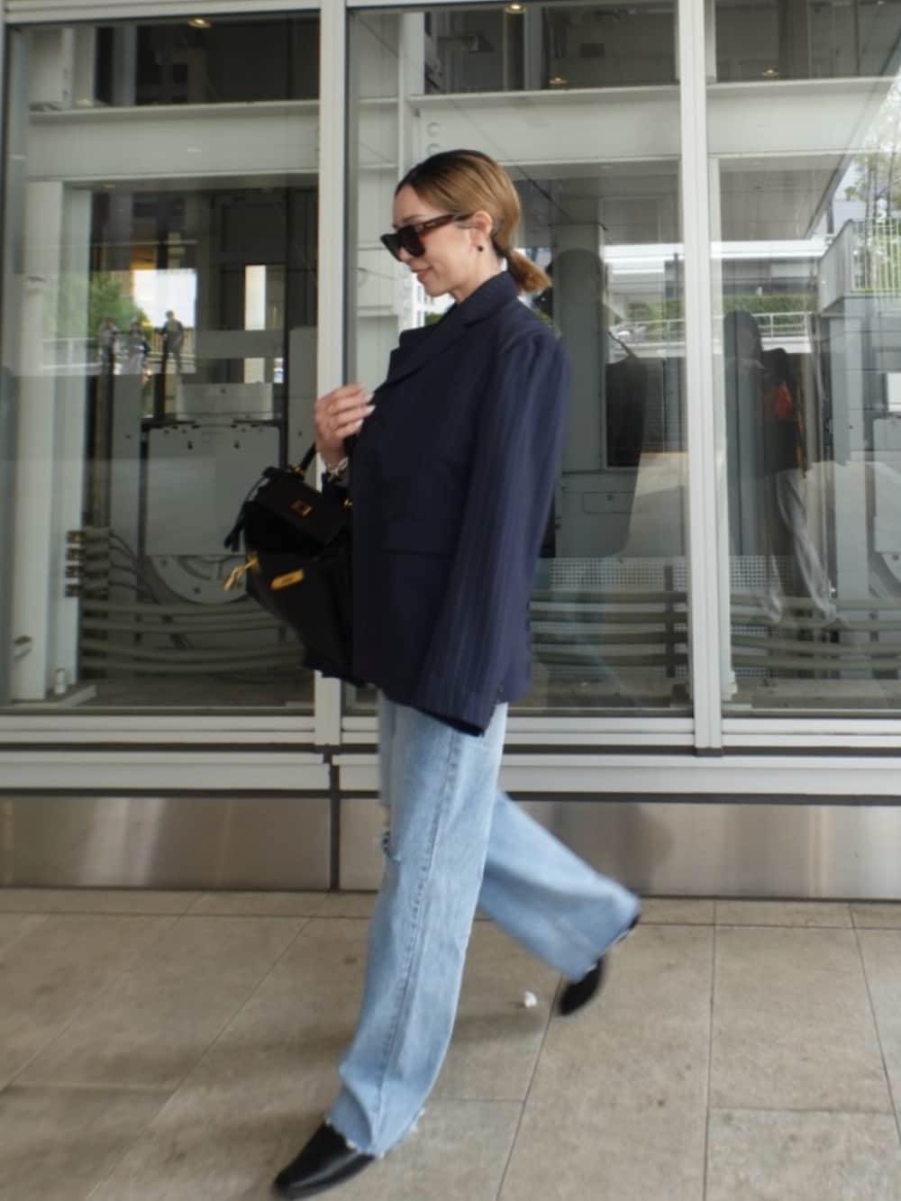 ブルー系のテーラードジャケット、ブルー系のデニムパンツ、ブラック系のバッグを着用したレディースの春コーディネートの2枚目の写真