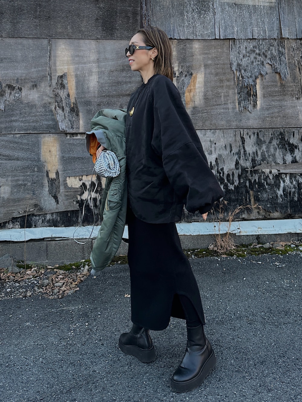 グリーン系のMA-1、シルバー系のバッグ、ブラック系のブーツを着用したレディースの冬コーディネートの3枚目の写真