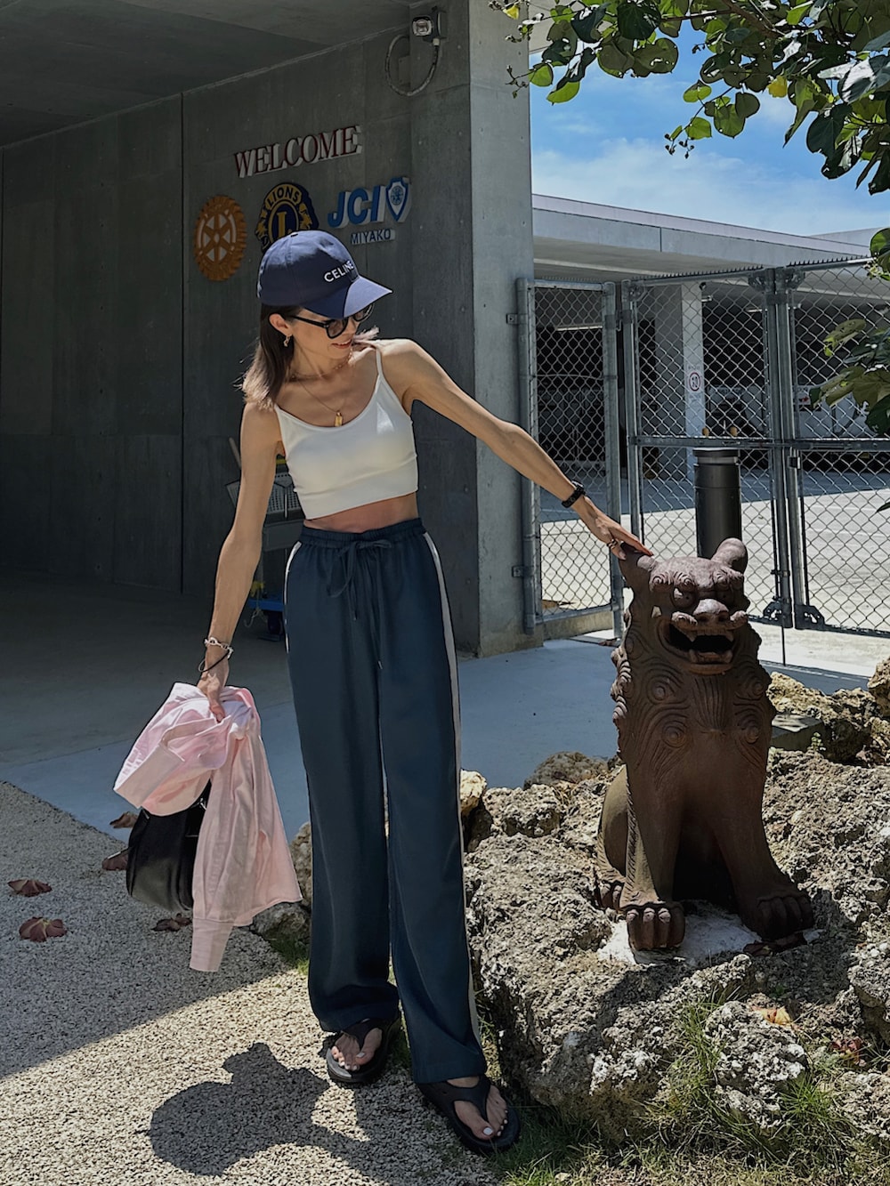 ブルー系のパンツ、ブラック系のサンダル、ブラック系のハンドバッグを着用したレディースの夏コーディネートの3枚目の写真