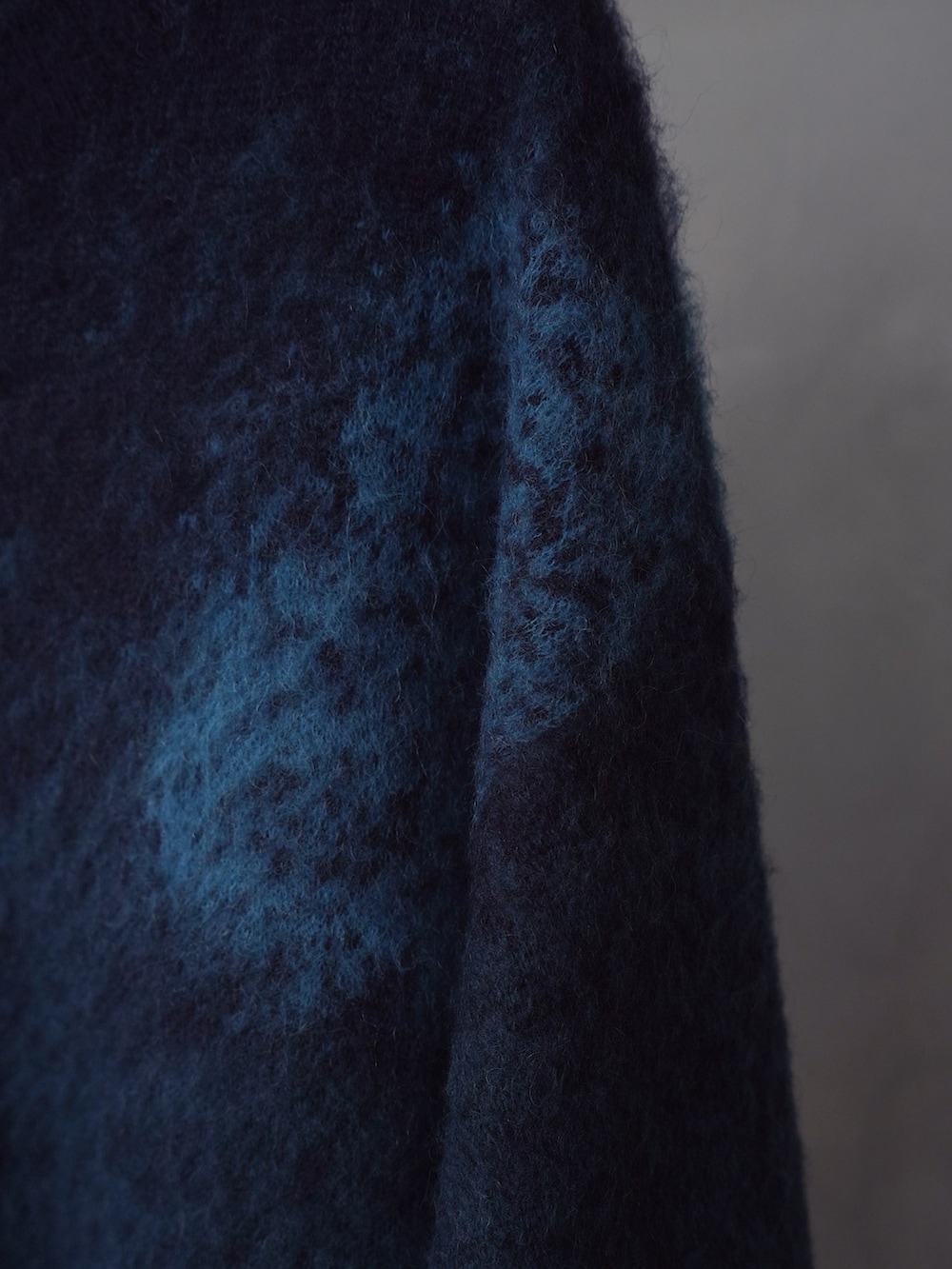 グレー系のチェスターコート、ブルー系のニット/セーター、ブラック系のスラックスを着用したメンズの冬コーディネートの4枚目の写真