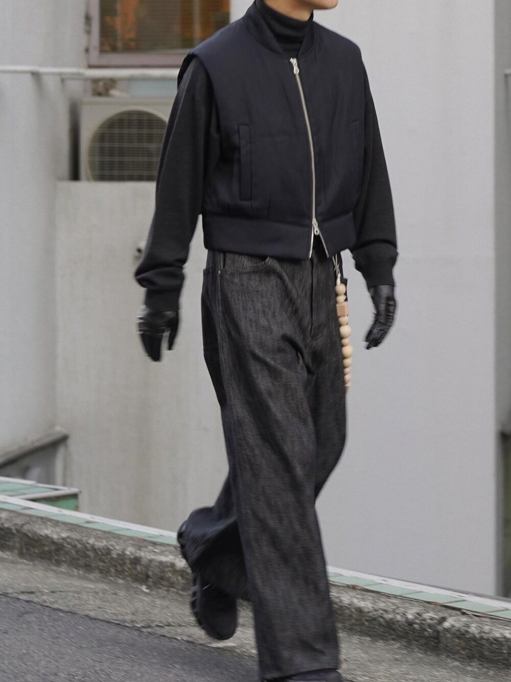 ブラック系のベスト、グレー系のニット/セーター、ブラック系のデニムパンツを着用したメンズの冬コーディネートの3枚目の写真