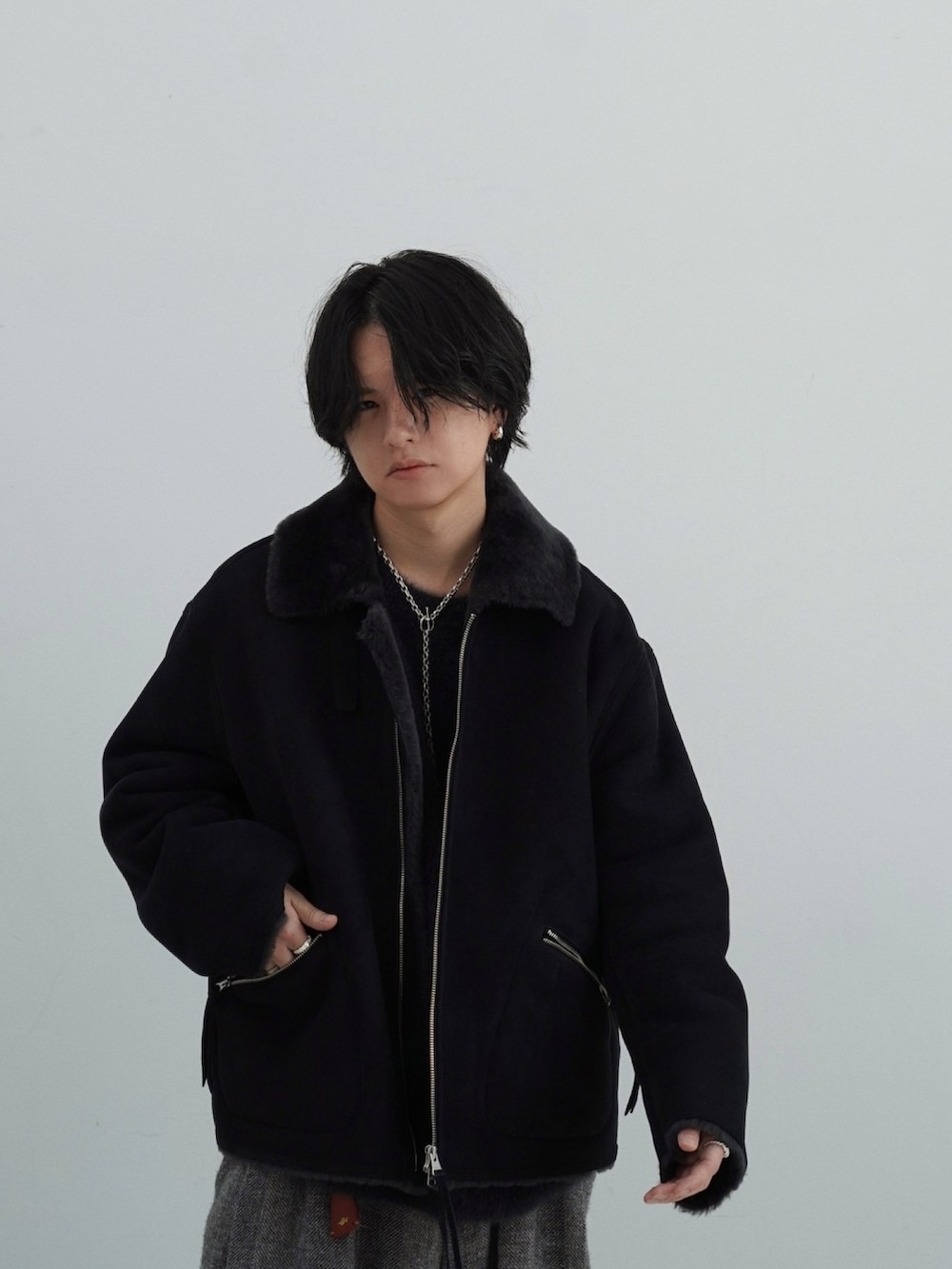 ブラック系のムートンコート、ブラック系のニット/セーター、グレー系のその他パンツを着用したメンズの秋コーディネートの3枚目の写真