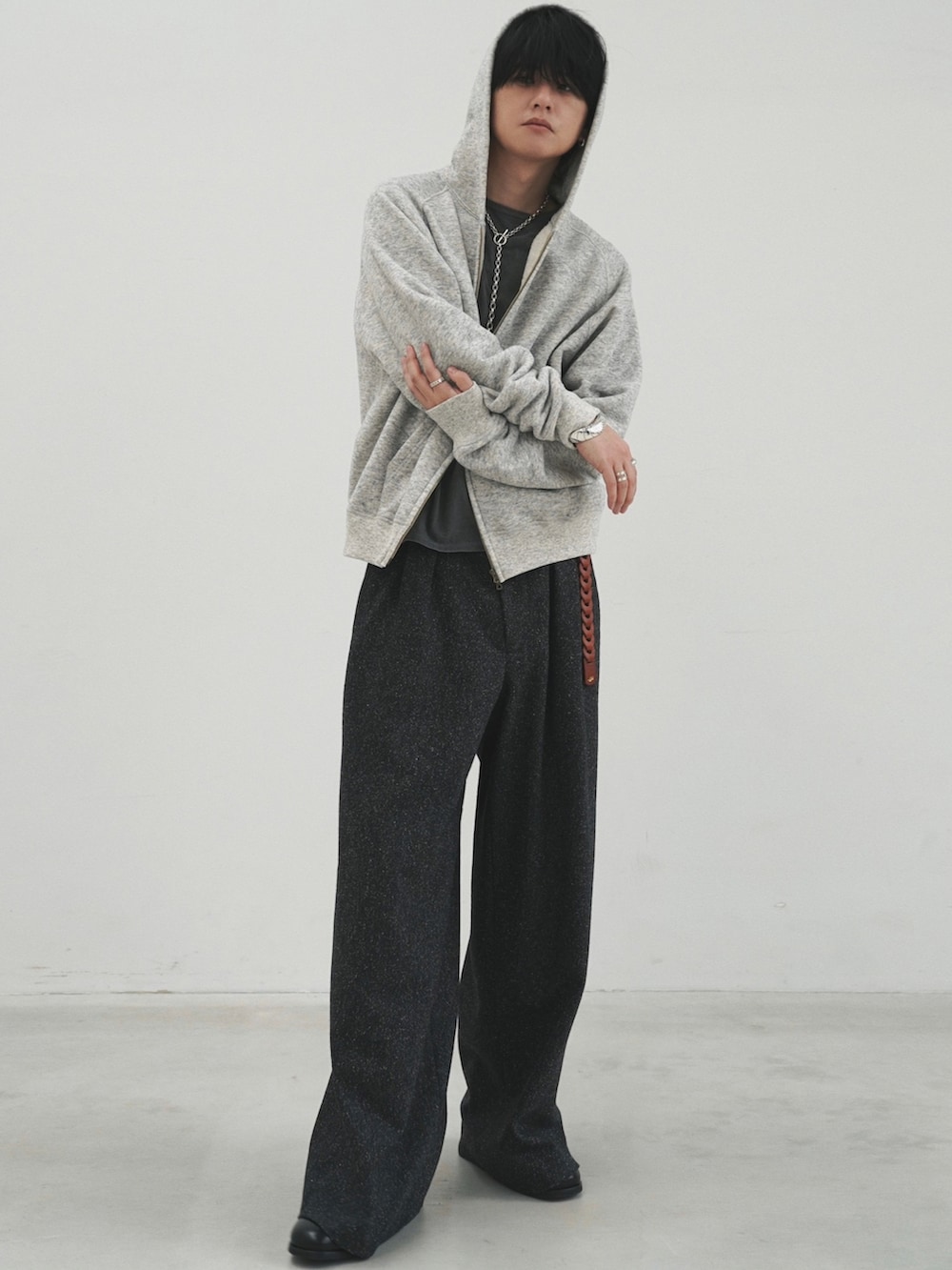 グレー系のパーカー、グレー系のTシャツ/カットソー、ブラック系のスラックスを着用したメンズの冬コーディネートの2枚目の写真