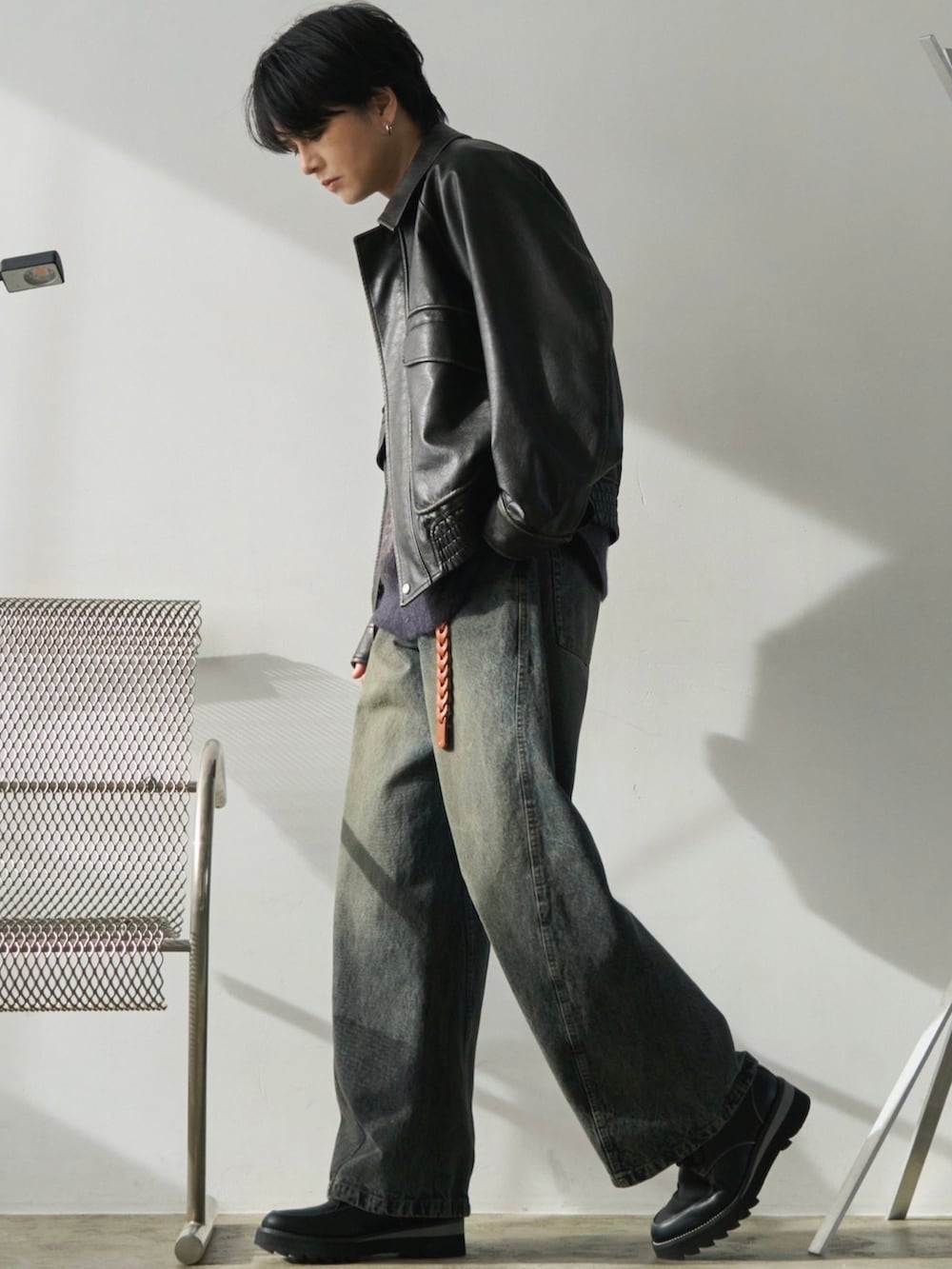 ブラック系のブルゾン、ブラウン系のニット/セーター、ブルー系のデニムパンツを着用したメンズの冬コーディネートの2枚目の写真