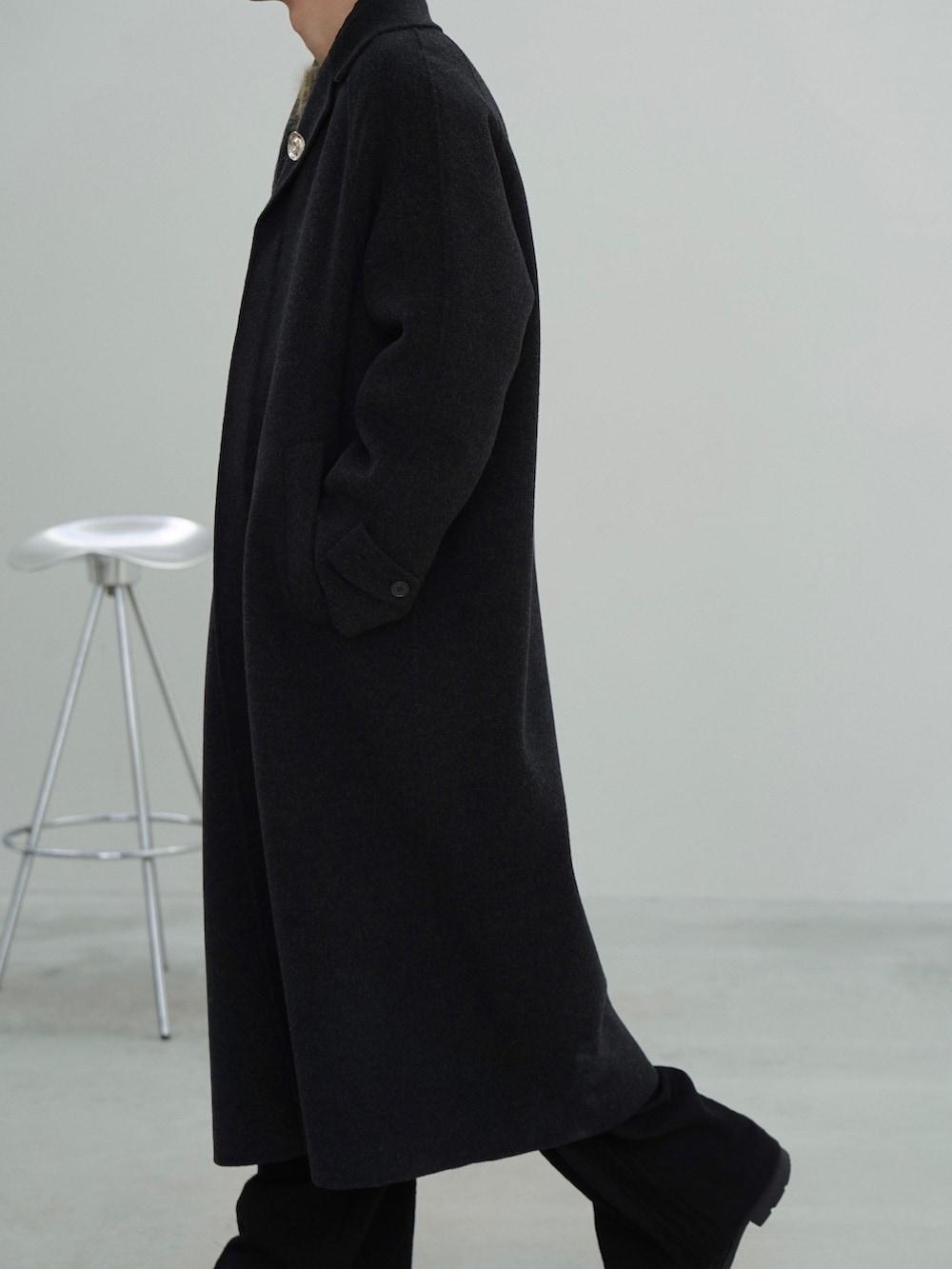 ブラック系のチェスターコート、ブラック系のテーラードジャケット、グリーン系のニット/セーターを着用したメンズの秋コーディネートの4枚目の写真