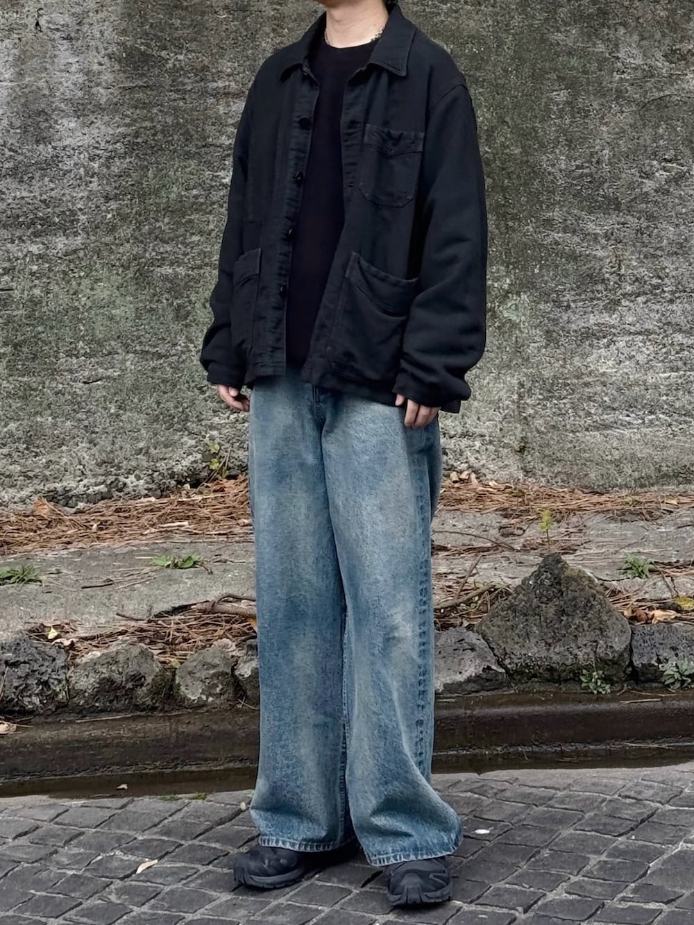 ブラック系のカバーオール、ブルー系のデニムパンツ、ブラック系のスニーカーを着用したメンズの春コーディネートの2枚目の写真