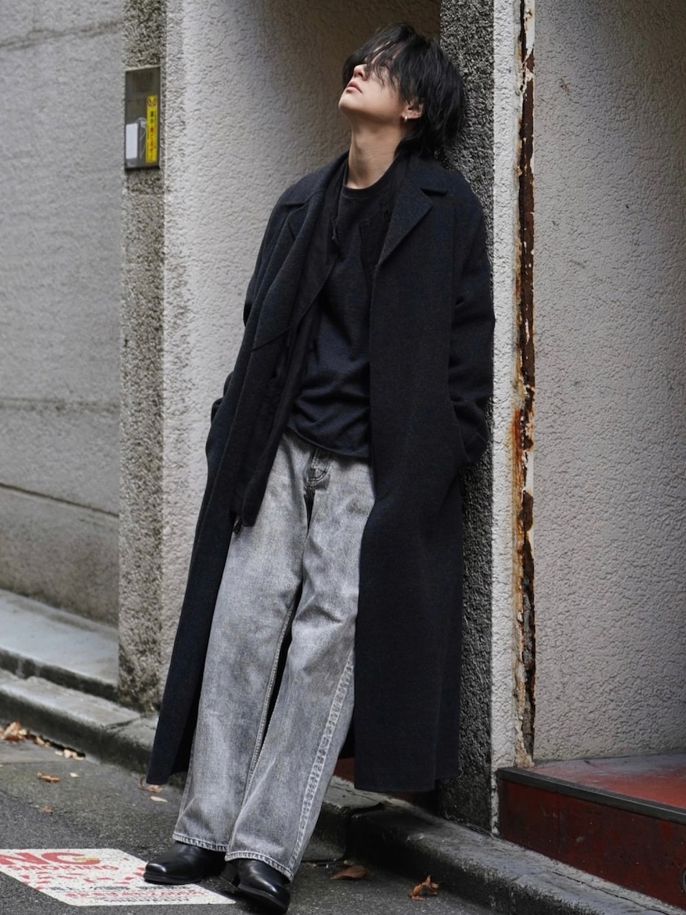 ブラック系のチェスターコート、ブラック系のTシャツ/カットソー、ブラック系のブーツを着用したメンズの冬コーディネートの2枚目の写真