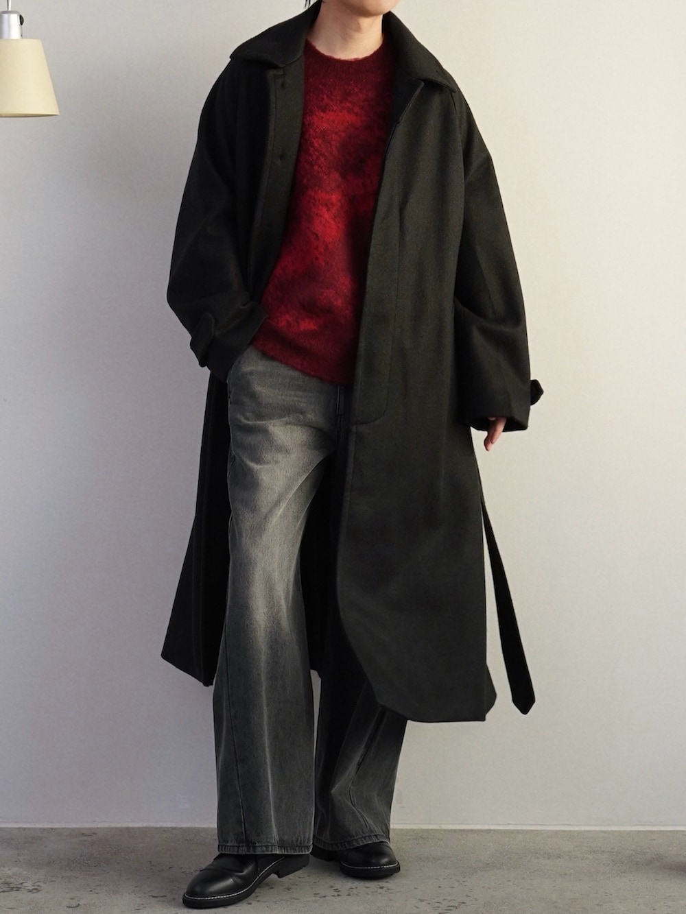 レッド系のニット/セーター、グレー系のデニムパンツ、ブラック系のドレスシューズを着用したメンズの冬コーディネートの2枚目の写真