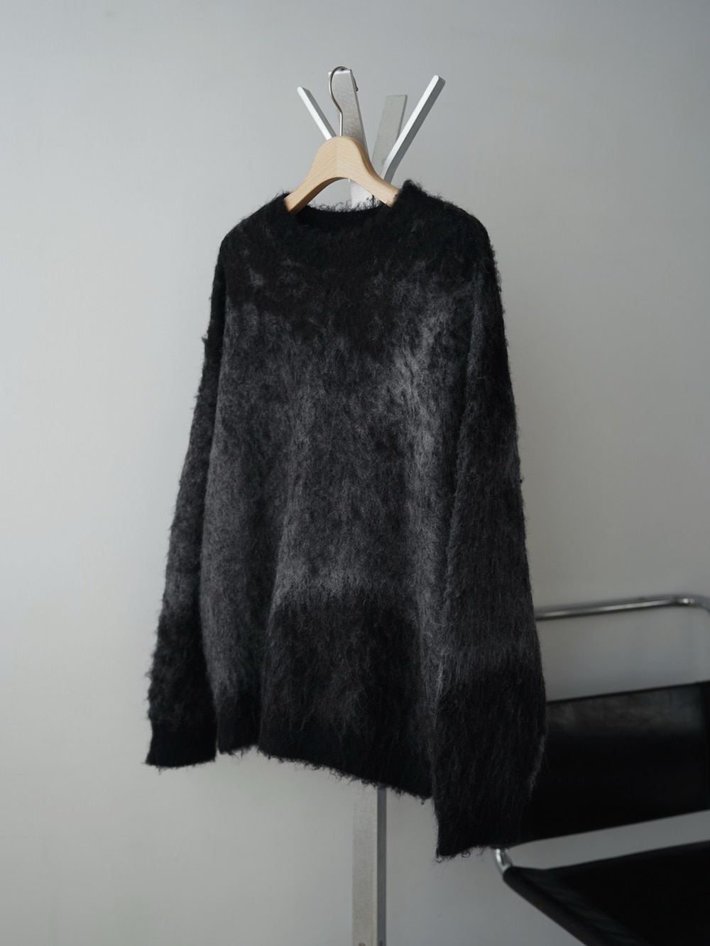 グレー系のチェスターコート、グレー系のニット/セーター、ブラック系のその他パンツを着用したメンズの冬コーディネートの5枚目の写真