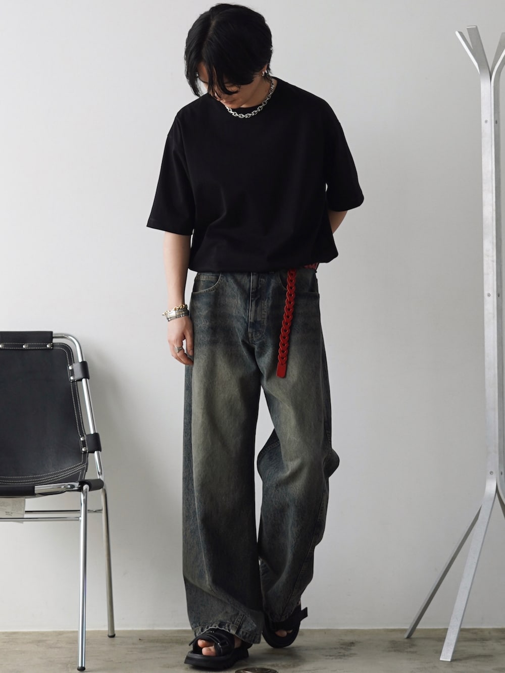 ブルー系のデニムパンツ、ブラック系のサンダル、ブラック系のTシャツ/カットソーを着用したメンズの春コーディネートの2枚目の写真