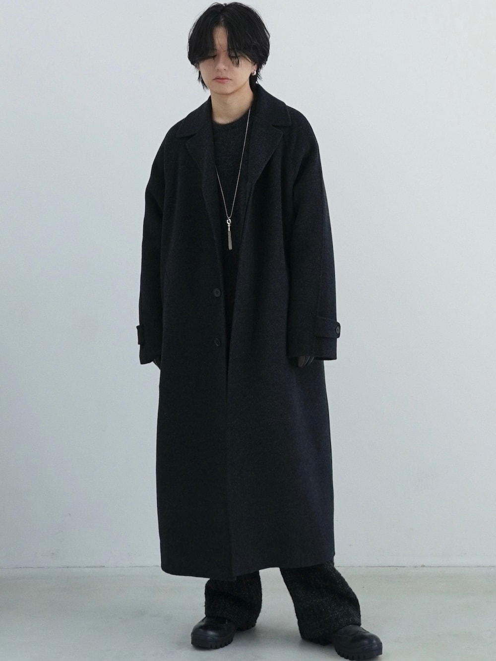 ブラック系のチェスターコート、ブラック系のニット/セーター、ブラック系のその他パンツを着用したメンズの秋コーディネートの2枚目の写真