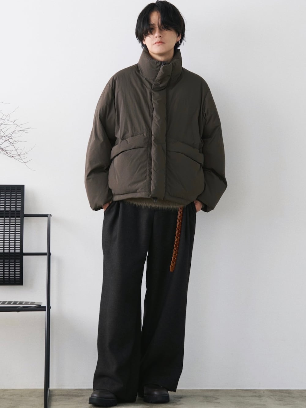 グリーン系のダウンジャケット/コート、グリーン系のニット/セーター、グレー系のスラックスを着用したメンズの秋コーディネートの2枚目の写真